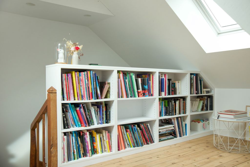 il s'agit d'une photo de combles aménagés avec une bibliothèque blanche réalisée sur mesure et faisant office de garde corps, il y a du parquet ancien