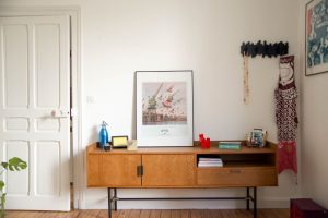 il s'agit d'un meuble en noyer avec des affiches, du parquet ancien, une porte ancienne et des murs blancs