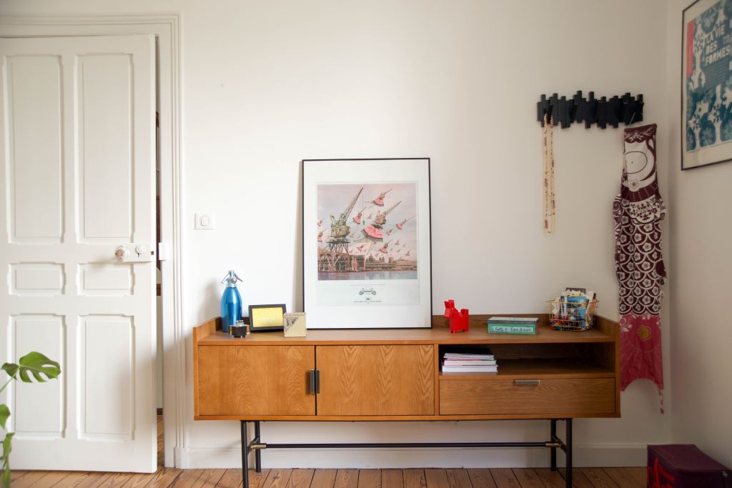 il s'agit d'un meuble en noyer avec des affiches, du parquet ancien, une porte ancienne et des murs blancs