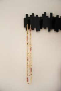 il s'agit d'un détail sur un porte manteaux noir graphique de chez Umbra, avec des colliers suspendus en coquillages de Tahiti