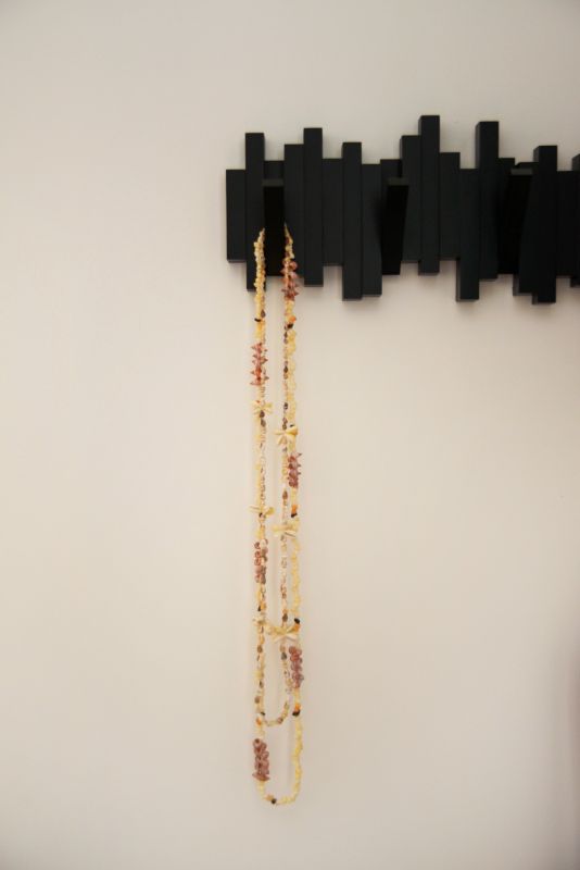 il s'agit d'un détail sur un porte manteaux noir graphique de chez Umbra, avec des colliers suspendus en coquillages de Tahiti