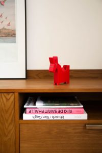 zoom sur détails d'un meuble en noyer avec livres sur Van Gogh et Munch et un autre de Niki de Saint Phalle, ainsi d'un porte post it en forme d'âne rouge de chez Pa Design, on aperçois aussi le coin d'un cadre avec une affiche de l'ile aux machines à Nantes