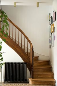 photo d'un escalier rénové en orme, le sol est en carreau de ciment ancien et radiateur en fonte noir