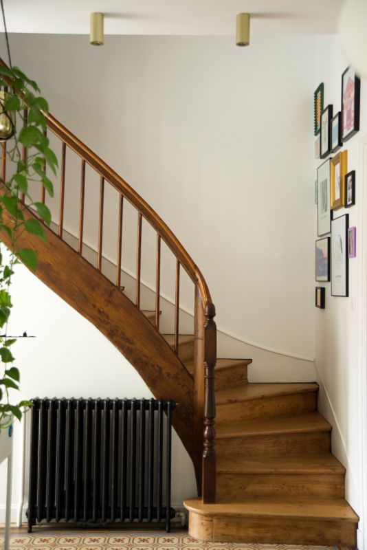 photo d'un escalier rénové en orme, le sol est en carreau de ciment ancien et radiateur en fonte noir
